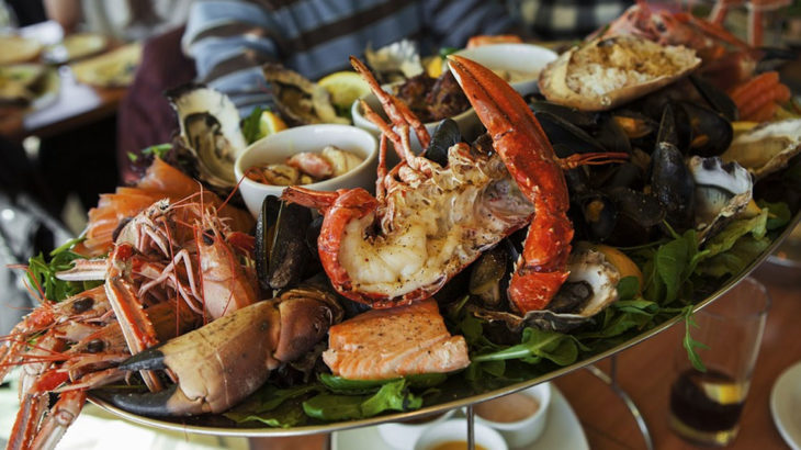 a plate of various seafood being presented by a server